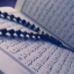 A close-up of prayer beads resting on an open Quran page, depicting Islamic faith and worship.